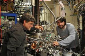 University of Utah chemistry Professor Scott Anderson and doctoral student Bill Kaden work on the elaborate apparatus they use to produce and study catalysts, which are substances that speed chemical reactions without being consumed. The world economy depends on catalysts, and the Utah research is aimed at making cheaper, more efficient catalysts, which could improve energy production and reduce emissions of Earth-warming gases. Credit: William Kunkel, University of Utah. 