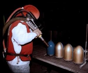 Using plastic media blasting to remove powder coatings from parts.