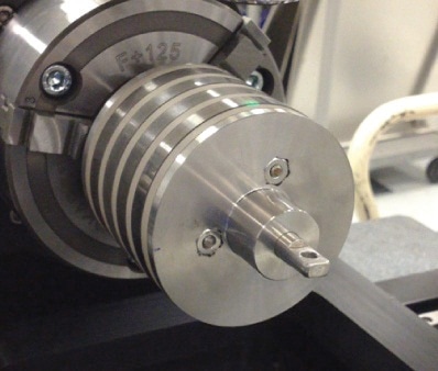Metal corrosion coupons mounted on a cylindrical jig on the NPFLEX rotational stage chuck.