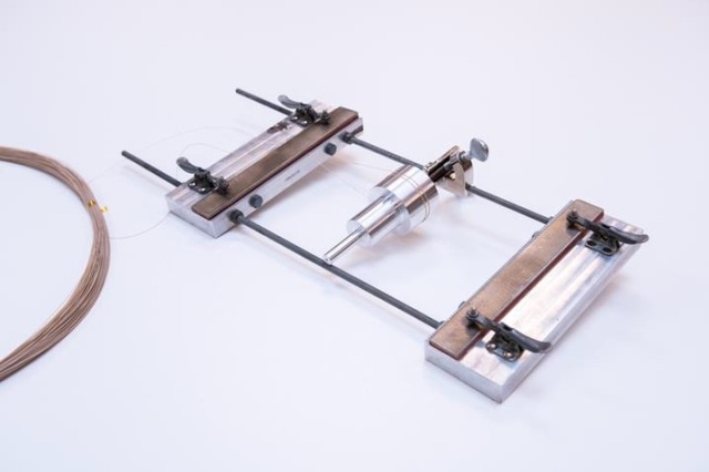 Test fixture used for bend radii testing. The Multiple radii test cylinder is in the middle of the fixture, and the silicone padded spring-loaded clamps are on the ends.