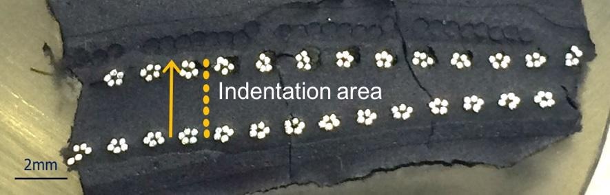 Cross-section of the tire sample embedded in epoxy, polished and ready for testing. The multiple polymer layers are apparent in the cross-section. A vector of tests was performed along the yellow line across the sample, proceeding upward.
