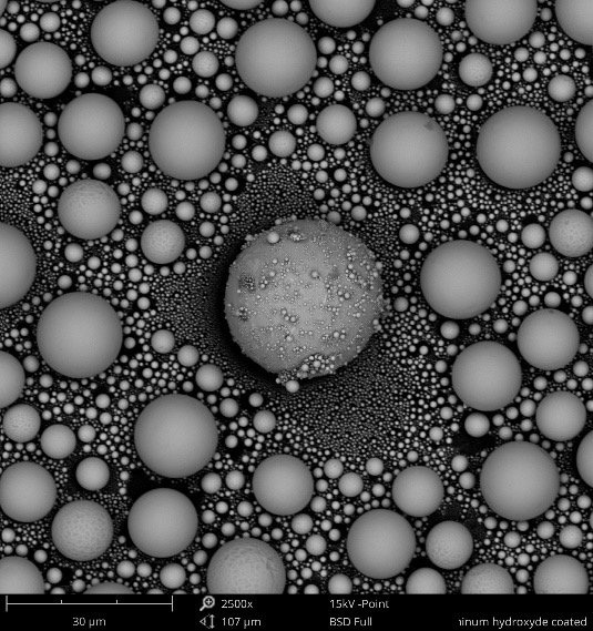 BSE images of tin balls at 5 kV (left) and at 15 kV (right). With the lower voltage, the carbon contamination on top of the sample becomes visible. When the voltage is increased, the deeper penetration enables the imaging of the tin ball surface underneath the carbon spots.