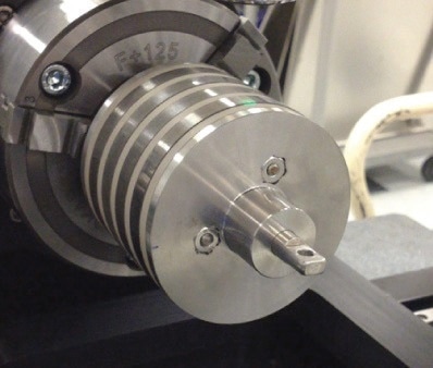 Metal corrosion coupons mounted on a cylindrical jig on the NPFLEX rotational stage chuck.