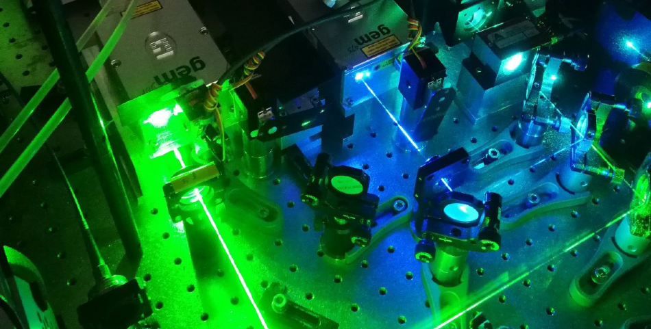 Photograph of the laser compartment of a widefield microscope for SMLM with the beam paths of the gem 473 (blue) and gem 561 (lime).