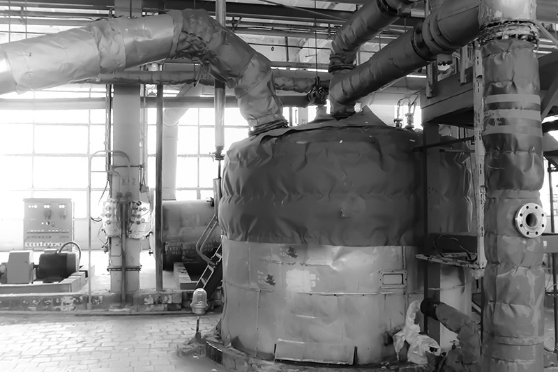 Large iron heat exchanger. tank, reactor, distillation column in thermal insulation of fiberglass and mineral wool of galvanized steel in the industrial refinery petrochemical plant shop.