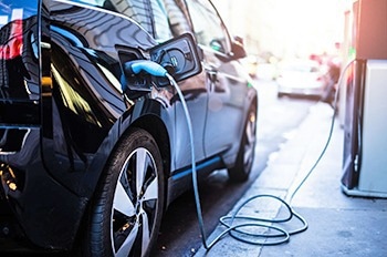Blue electric vehicle and connector charging at a fast-charging station.