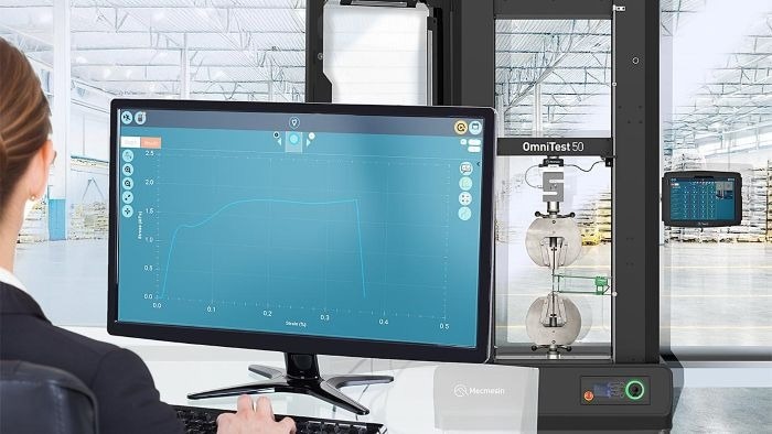 A high-capacity twin-column UTM performing a material properties analysis on a metal test piece. Large grips are required to keep the specimen secure under high tensile loads and an extensometer is essential instrumentation to accurately record these low values of elongation. The software screen displays a typical stress-strain curve of an elastic material under tension; showing the characteristic shape we use to calculate fundamental material properties, such as Young’s modulus of elasticity, from salient points on this curve