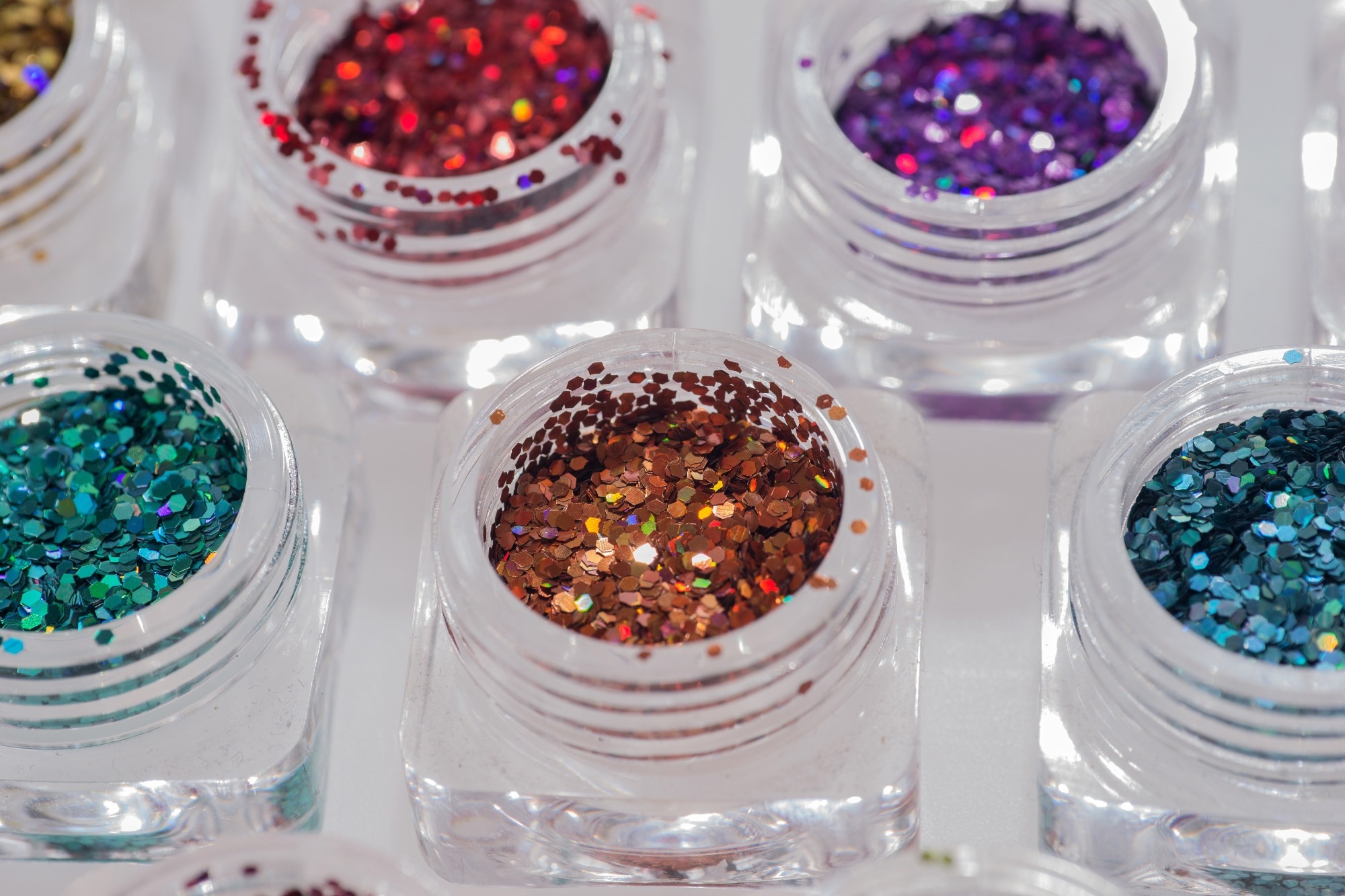 Close up image of red, purple, blue, and orange glitter in make up pots.