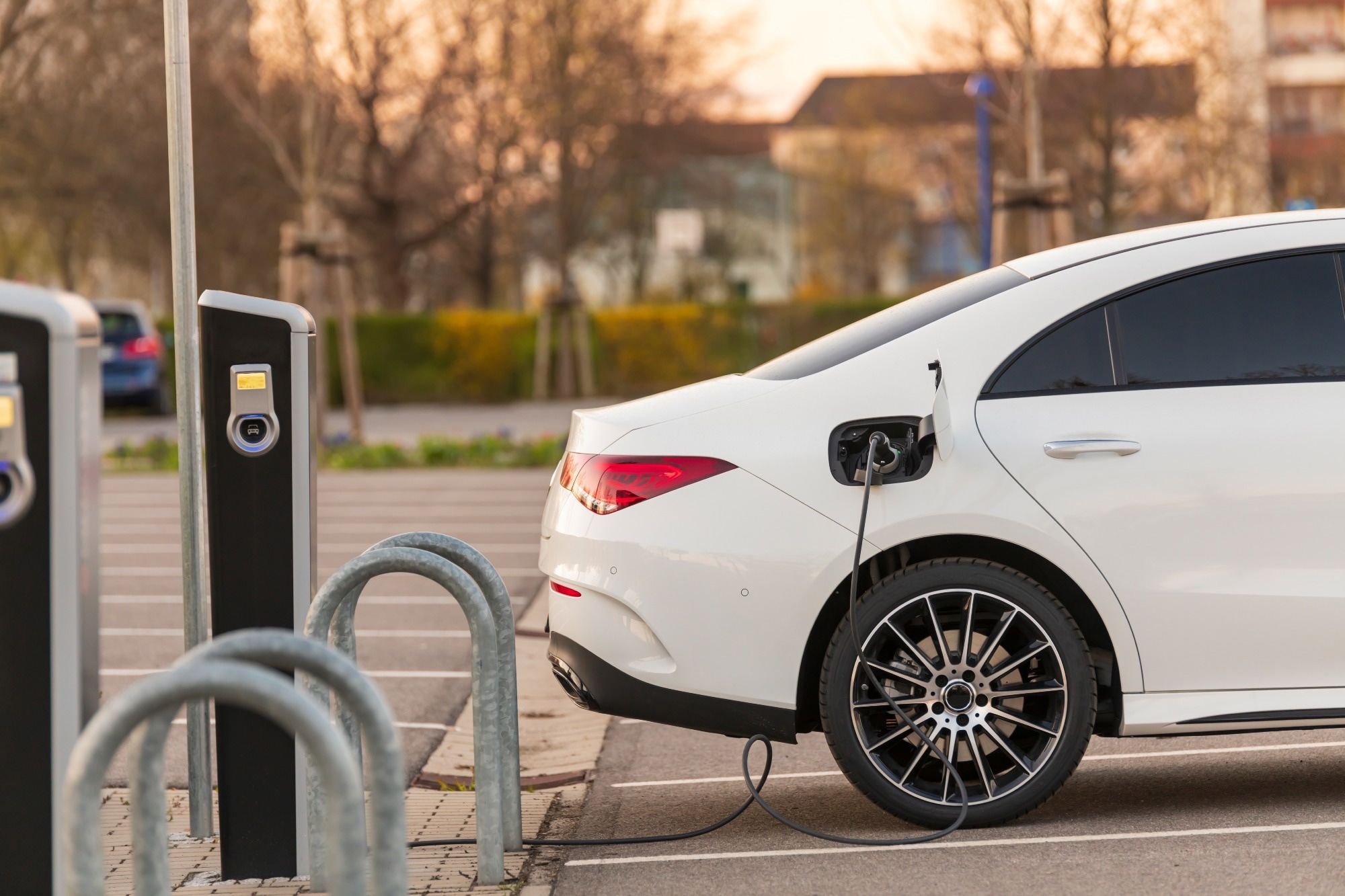 A white electric vehicle at a charging port being charged.