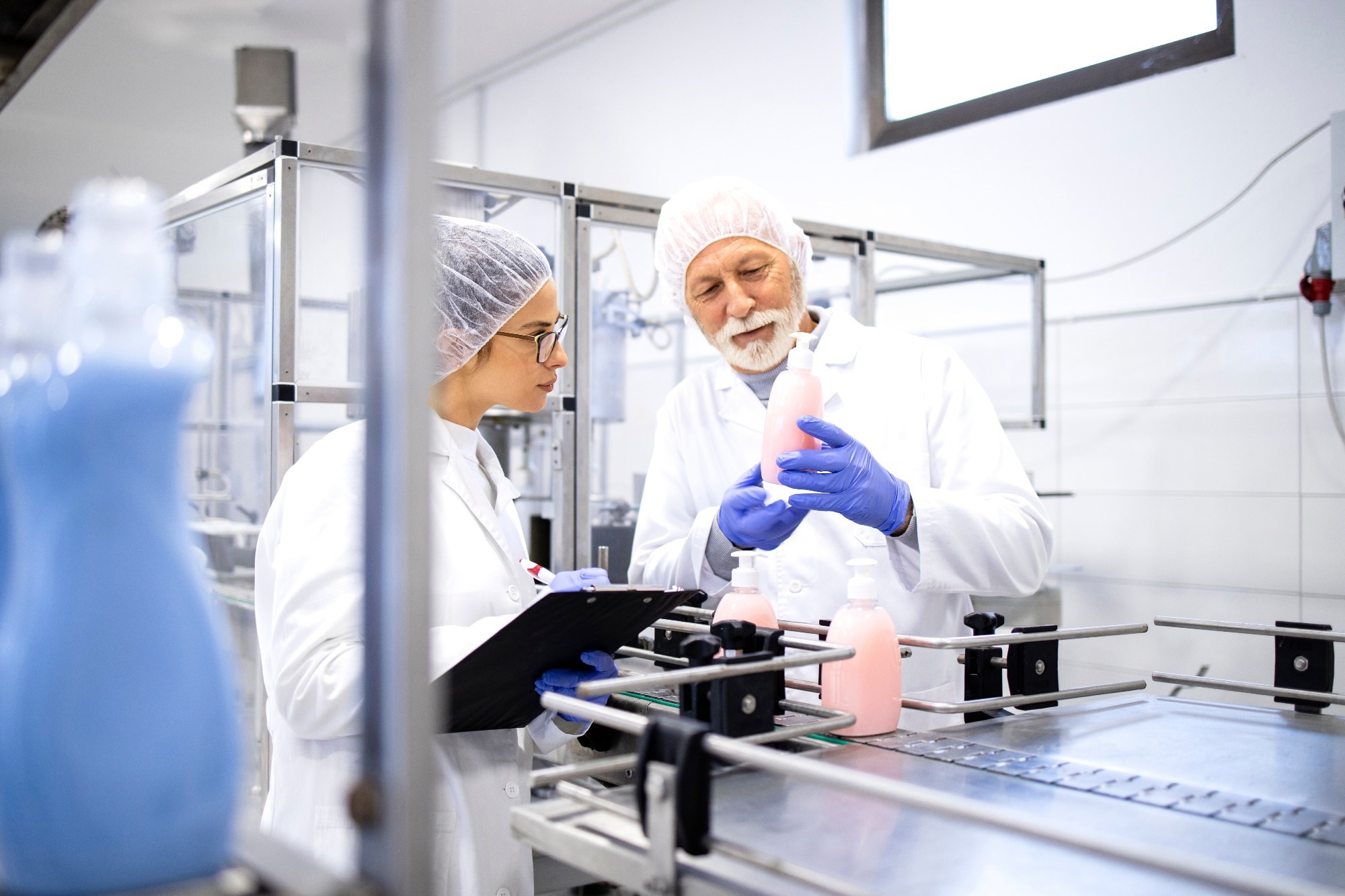 Shampoo production and workers standing by machine doing quality control of cleaning chemicals.