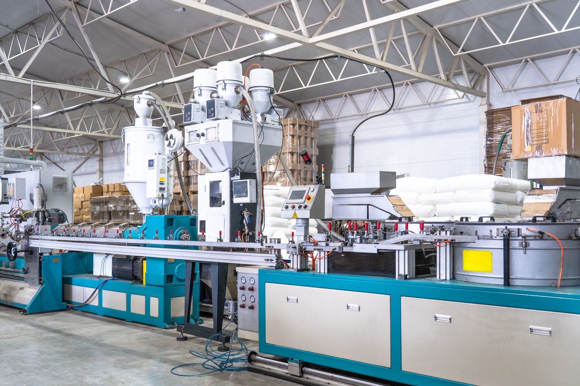 Plastic extrusion manufacturing machine in modern industrial factory, automated polymer processing line for plastic products production with raw material and control panels