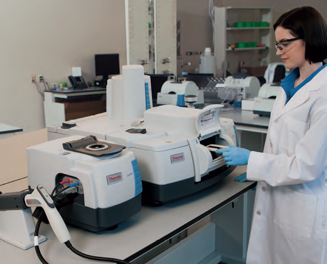 A scientist wearing a lab coat, safety goggles and blue nitrile gloves uses the Thermo Scientific Nicolet iS50 FT-IR spectrometer