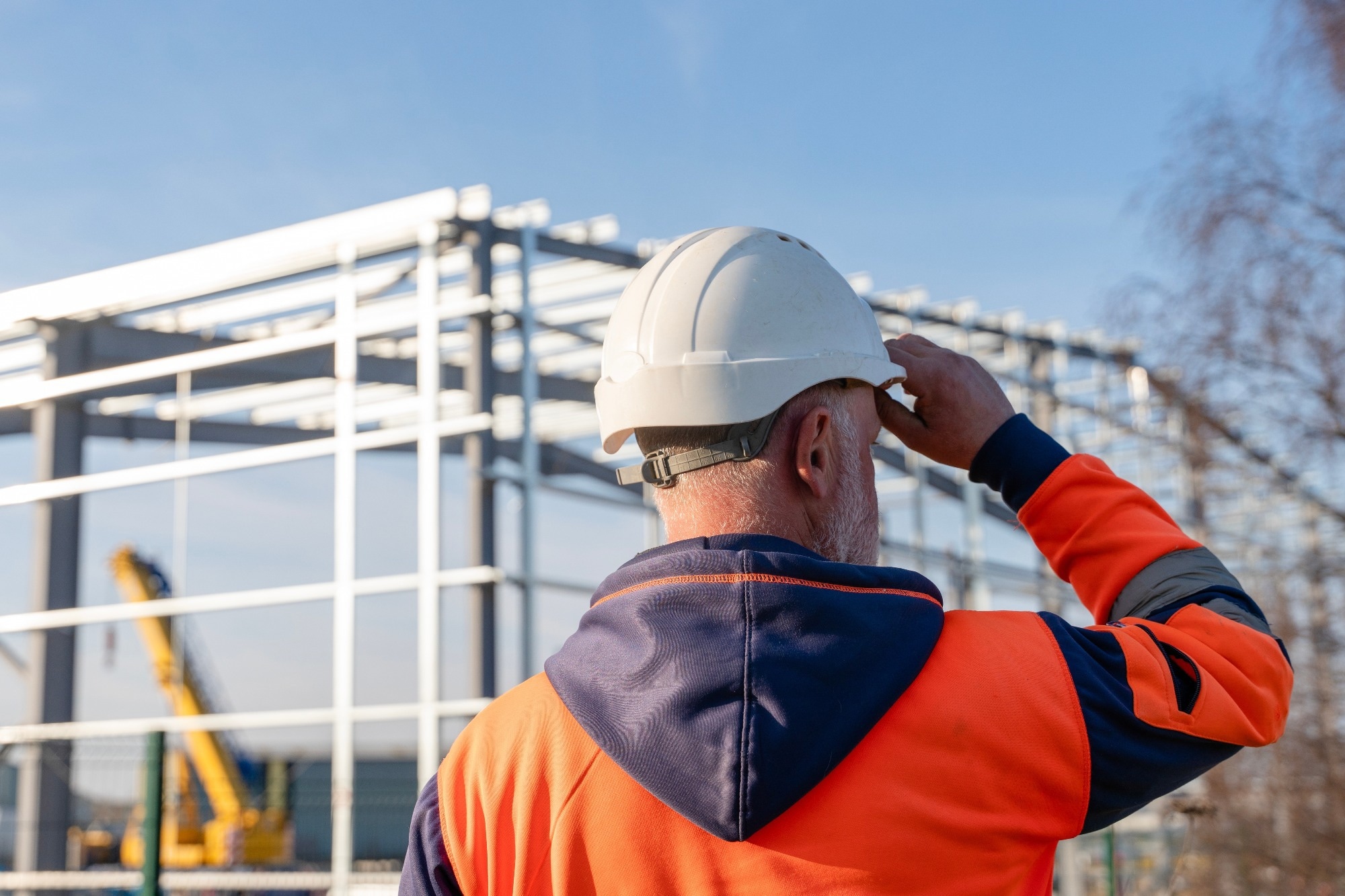 Construction worker oversees steel framework assembly at construction site during early morning hours