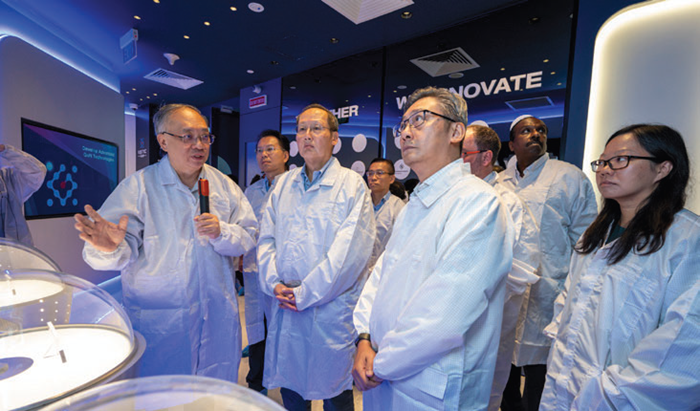 Scientists in singapore wearing lab coats look at the instrumentation.