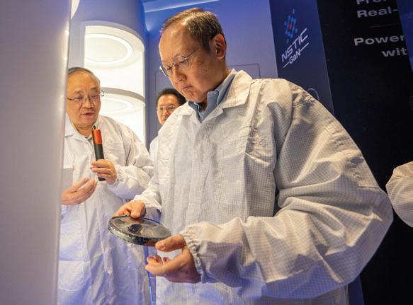 One of the employees look at the equipment while a man peers over his shoulder.