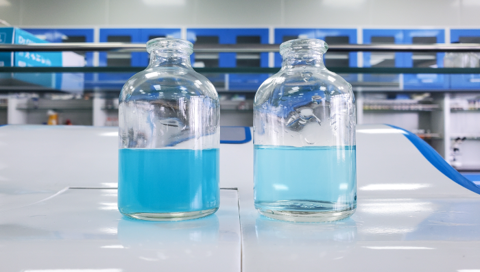 Two vials filled with blue liquid. The liquid on the left shows the sample pre-homogenization and the right shows the sample after homogenization. The sample is a lighter blue after processing.