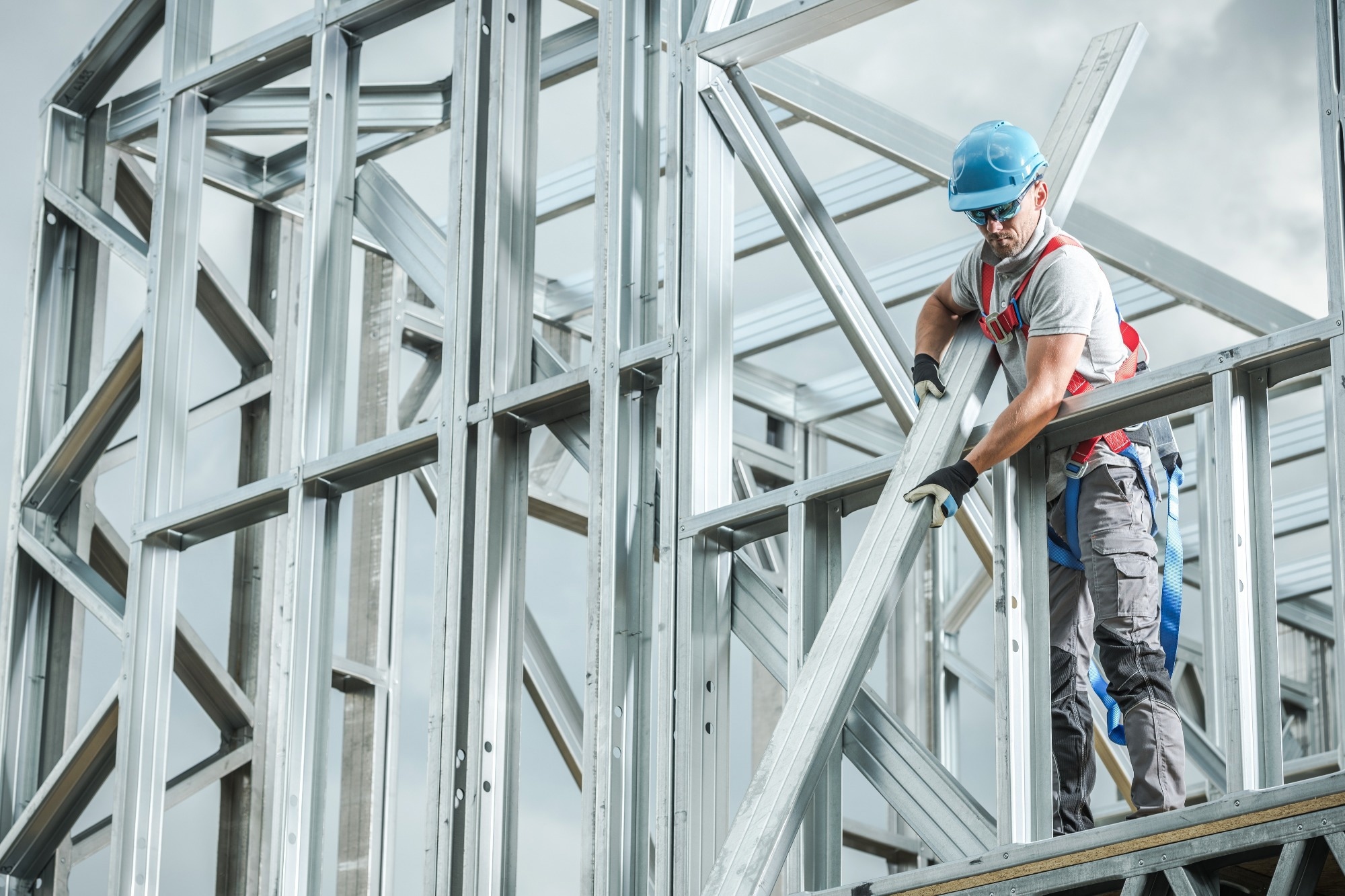 A construction worker places a steel beam in place high up in a construction site.