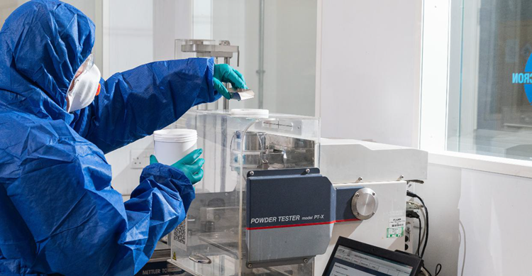 Scientist wearing PPE using a powder tester