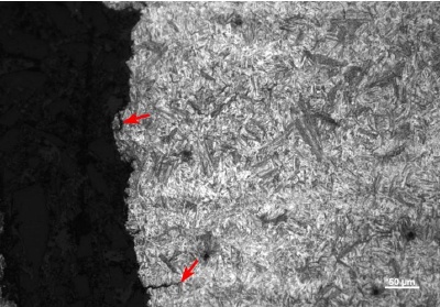 Photomicrograph of untempered martensite in a cracked coupling. Arrows indicate secondary cracks.