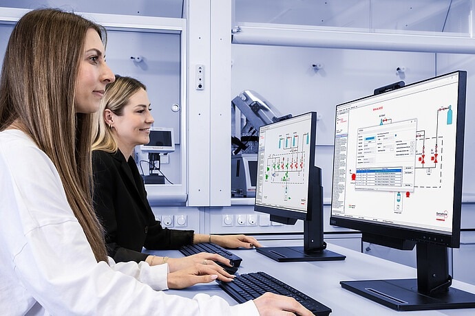Two women look at the work flow of high-pressure experiments and temperature control.