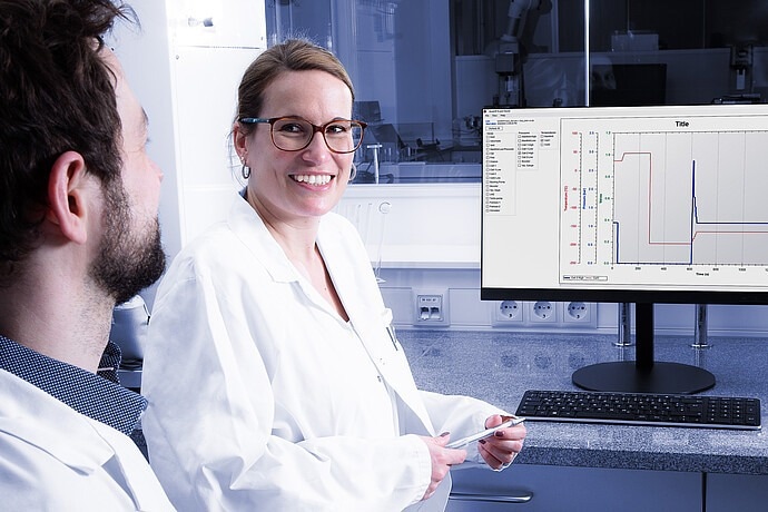 A man in plain clothes and a woman wearing a lab coat look at the pressure output from a spectrum.