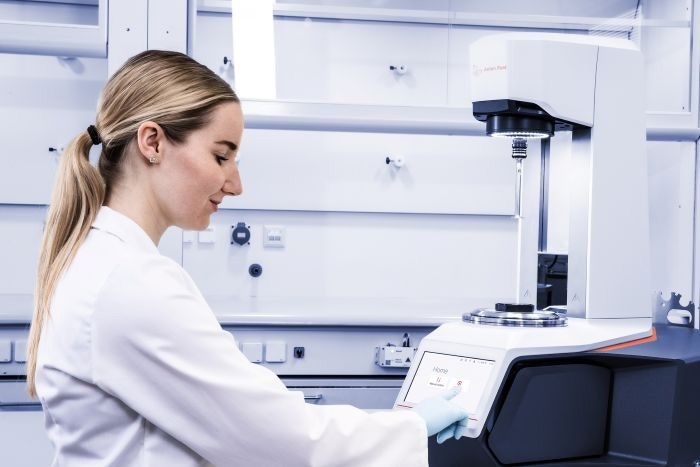 A woman in a lab coat uses the rheometer.