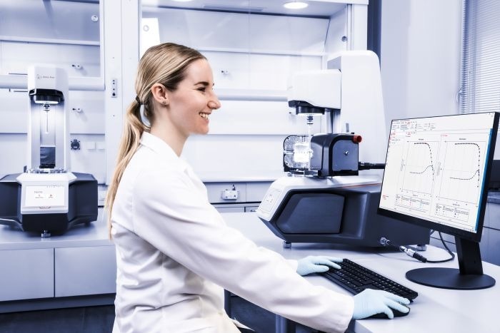 A woman in PPE looks at data from the equipment.