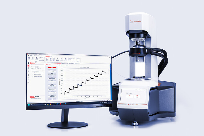 The software visible on a computer screen, sits next to the instrument. White background.