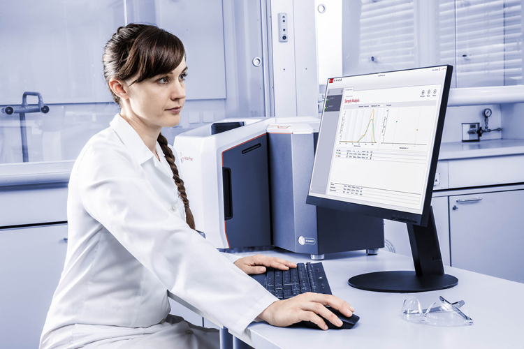A scientist analyzing the spectra received from the analyzer, she wears a white lab coat.