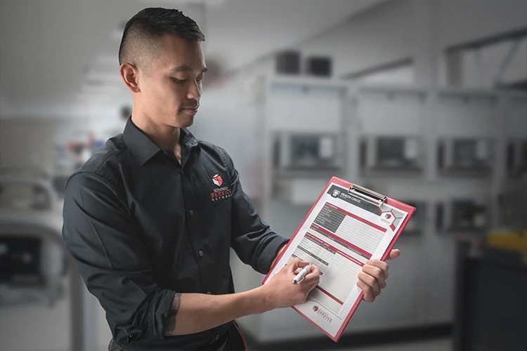 An engineer stands holding a clipboard pointing out the product details.