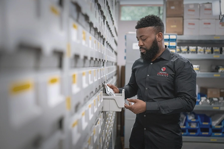 A SERVOTOUGH worker collecting an item from a small gray box.