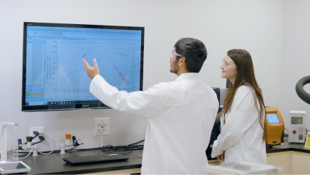 Two scientists analyzing findings on a large screen