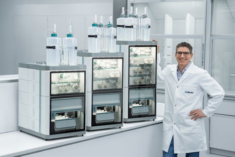 Male scientist wearing a labcoat stood by OMNIS hardware