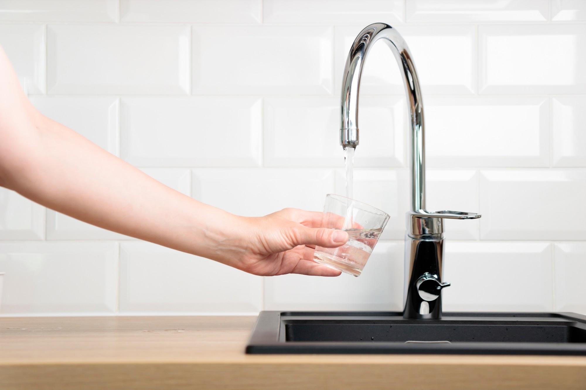 Glass cup being filled with tap water.