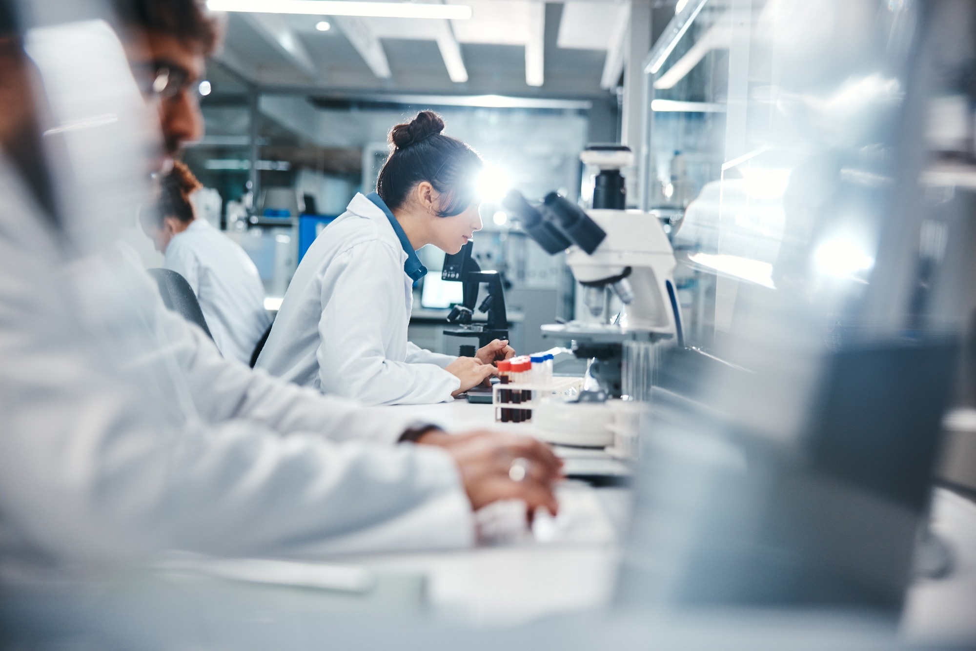 A team of scientists working in a laboratory, focusing on research with microscopes and test tubes. The image captures a collaborative research environment, which could align with the study of synthetic cells or biotechnological advancements.