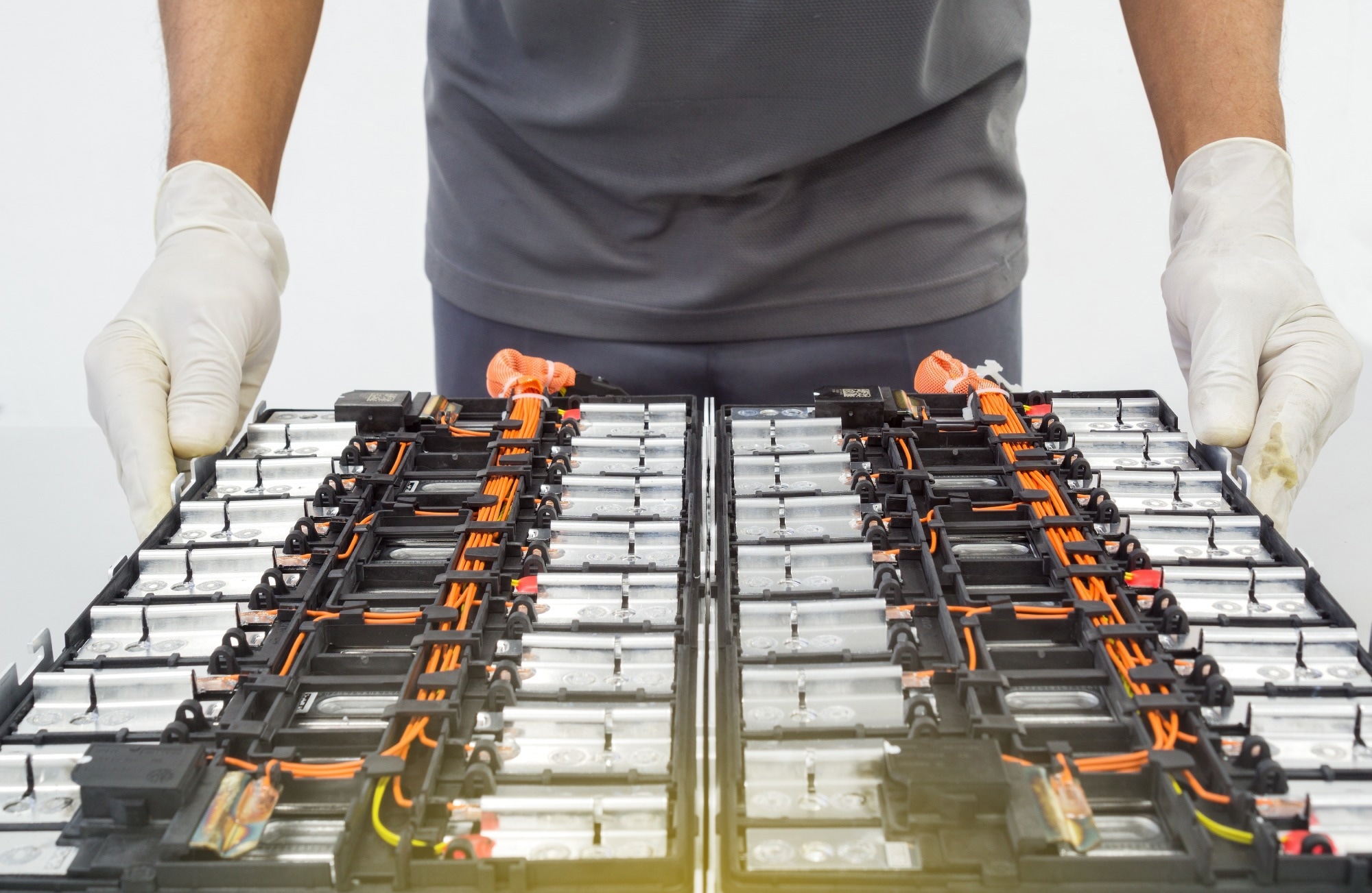 Close-up of a technician wearing gloves handling a lithium-ion battery module