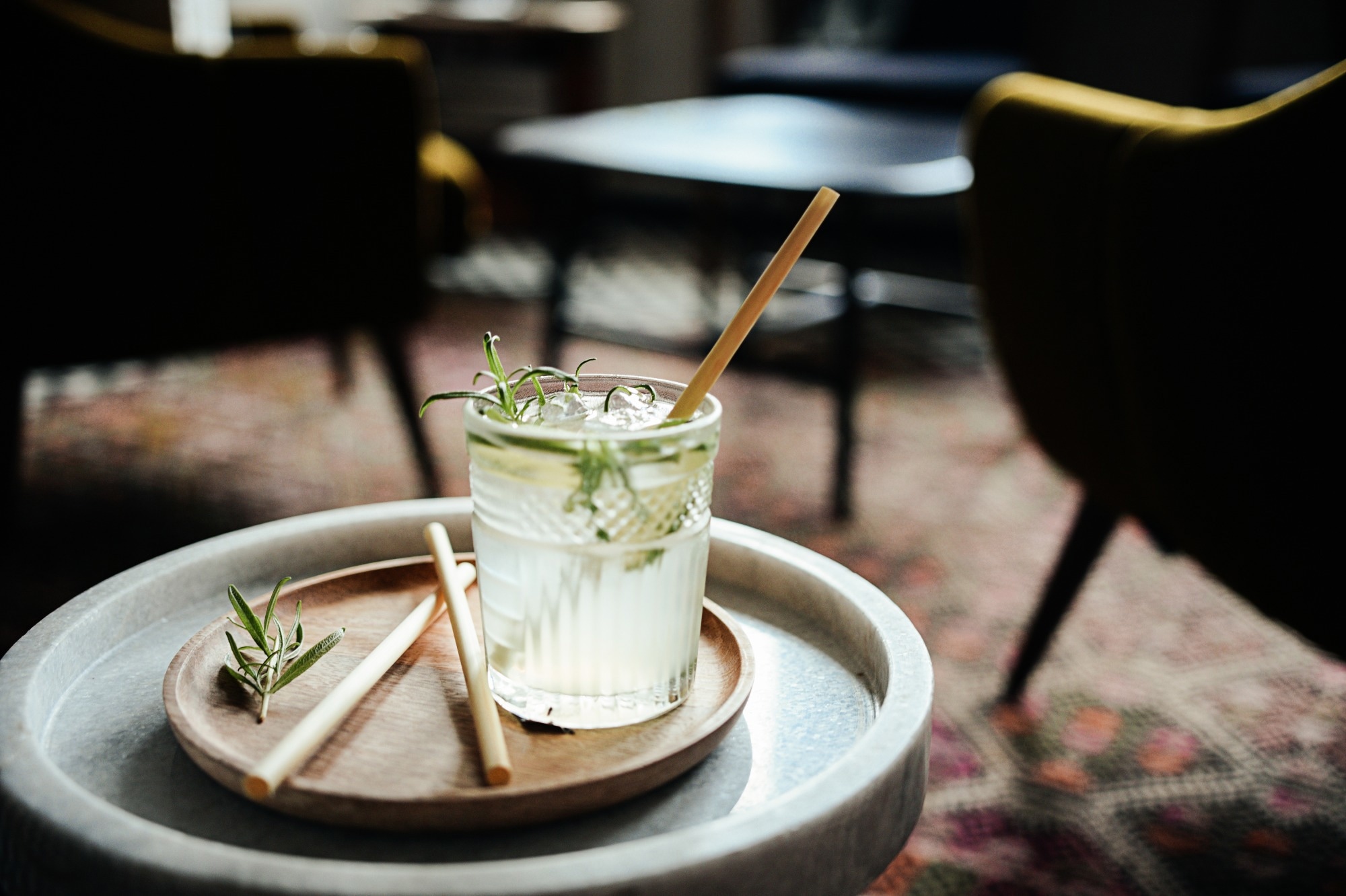 Alcohol cocktail drink with bamboo straws in bar interior on the table.