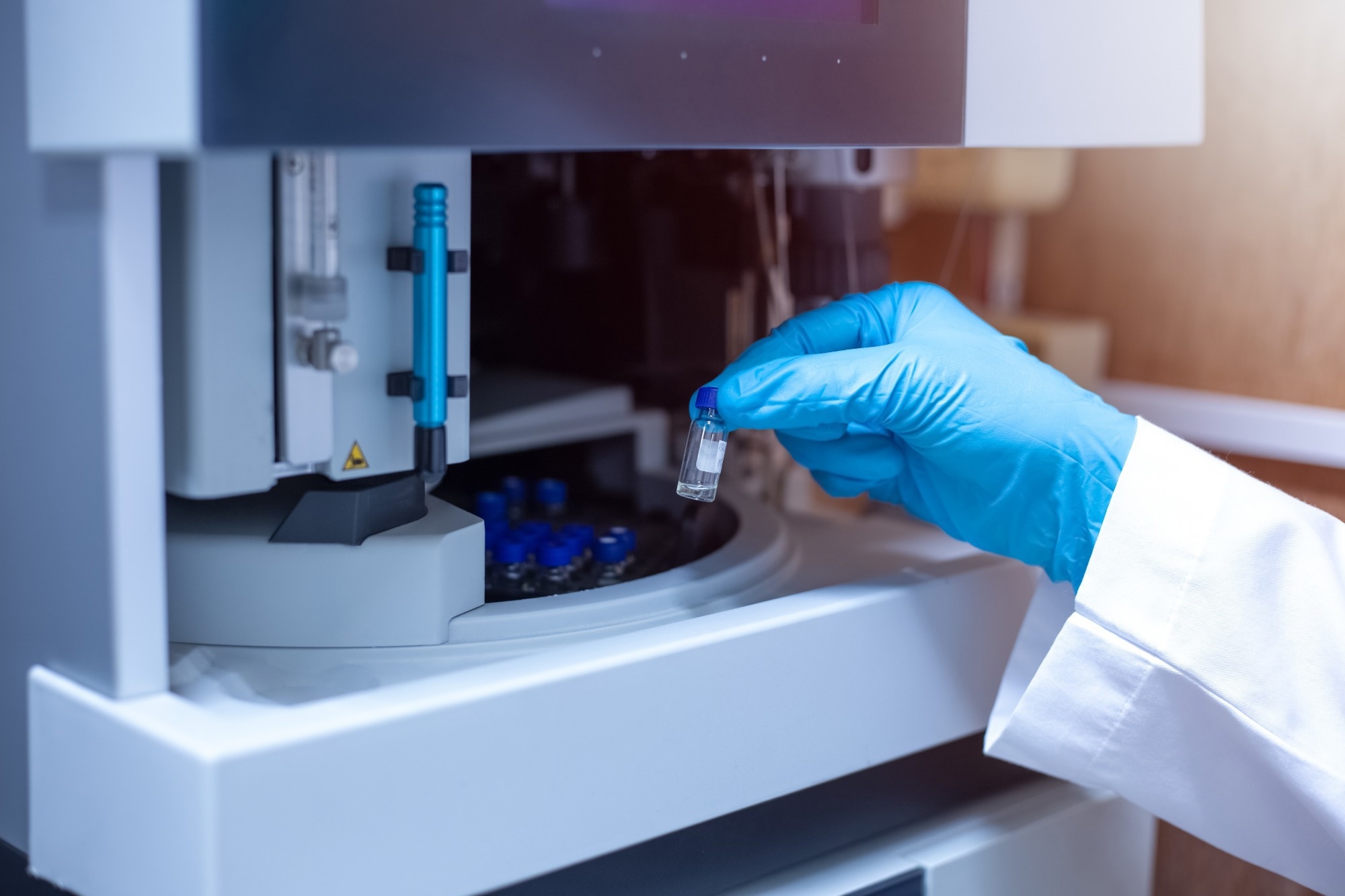 Scientist moving a vial of sample out from the tray autosampler of a spectrometer