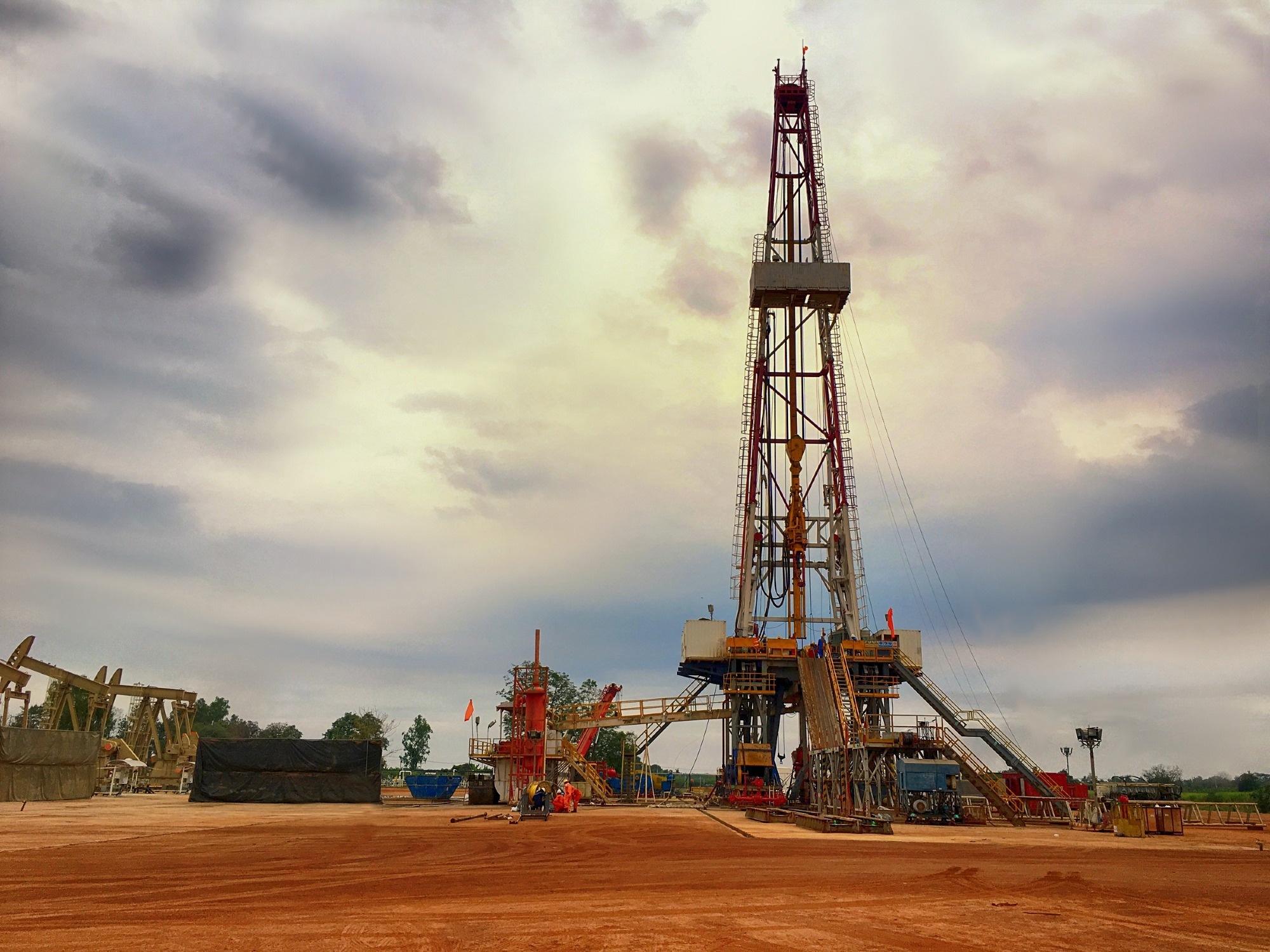 Oil and gas drilling rig onshore dessert with a cloudy sky.