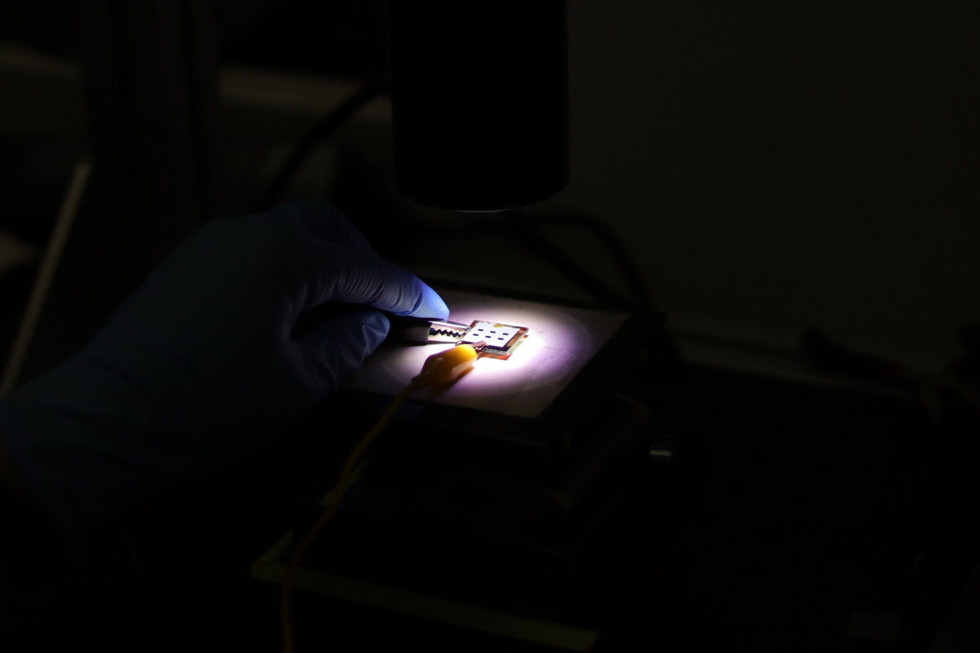 A perovskite solar cell being tested in a dark room lab.