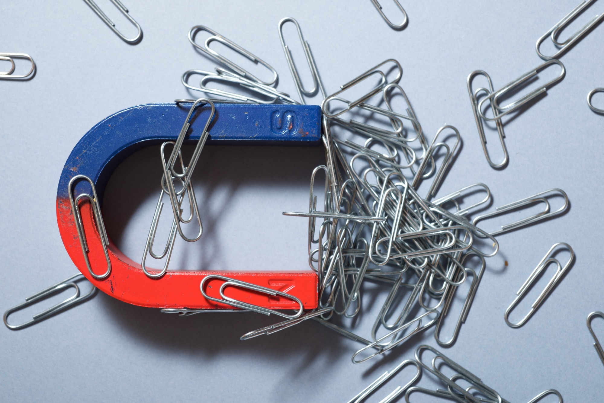 Image of a magnet attracting paper clips.