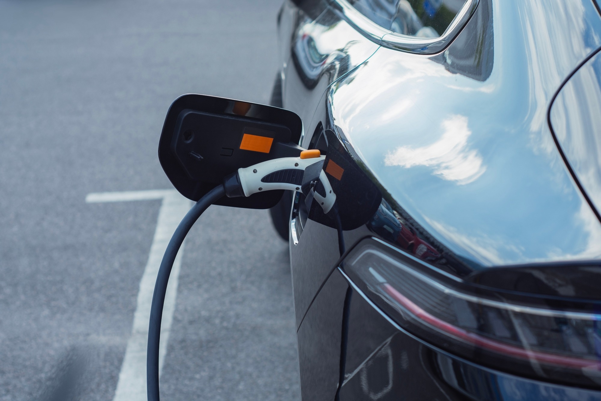 An EV with a charging lead attached to the car, the black car is being charged.